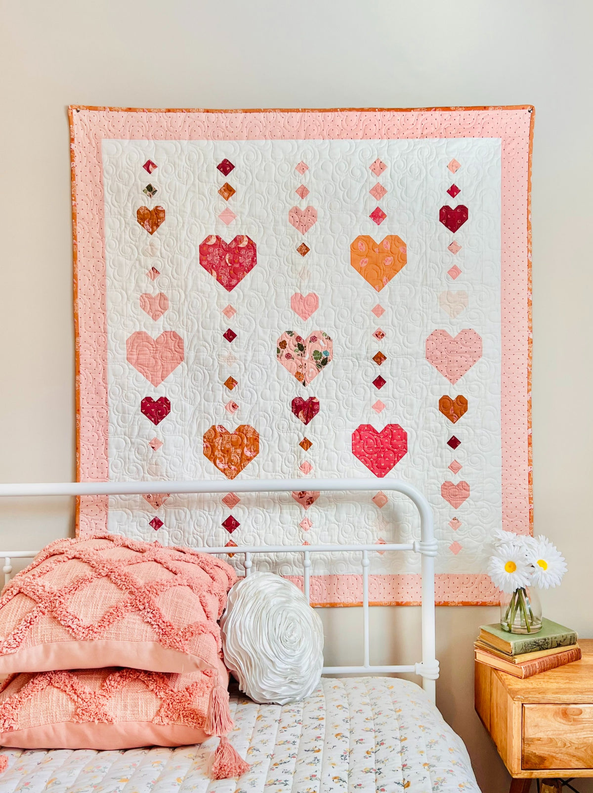 Heart on a String crib quilt hanging above a bed