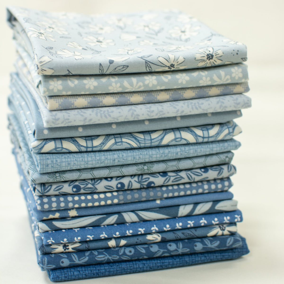 Blue Skies fat quarter bundle: a stack of 16 blue Moda fat quarters with florals, dots and blenders